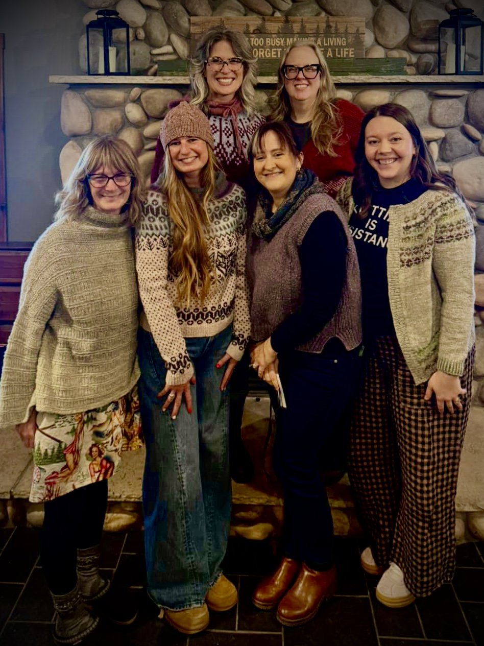 Brienne with fellow makers by a stone fireplace at the Up North Fiber Retreat